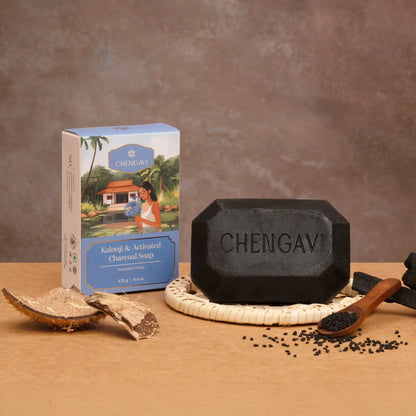 Black soap bar with packaging and ingredients on a wooden surface